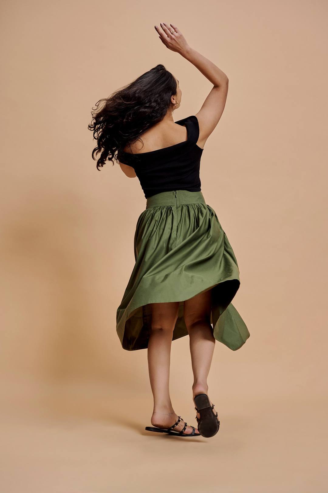 Women laughing and twirling in the studio, in black, red and olive