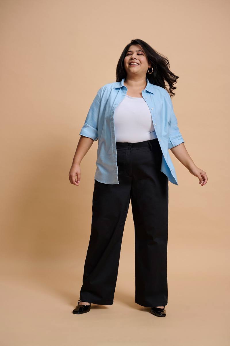 A woman laughing in a blue Oxford shirt and black trousers