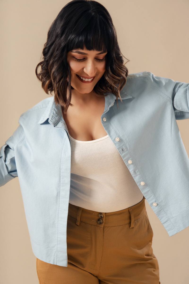 A woman in a blue cropped shirt and tan trousers