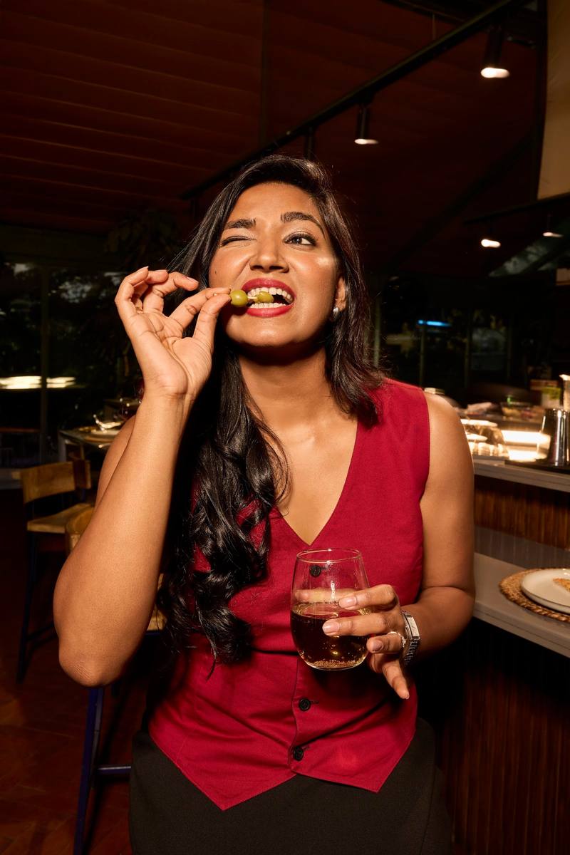 A woman laughing in a red waistcoat at dinner